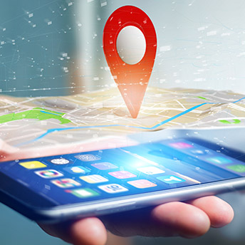a gps pin sticking in a map above a cellphone