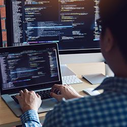 Rear view of software developers is sitting serious analyzing data on the computer screen